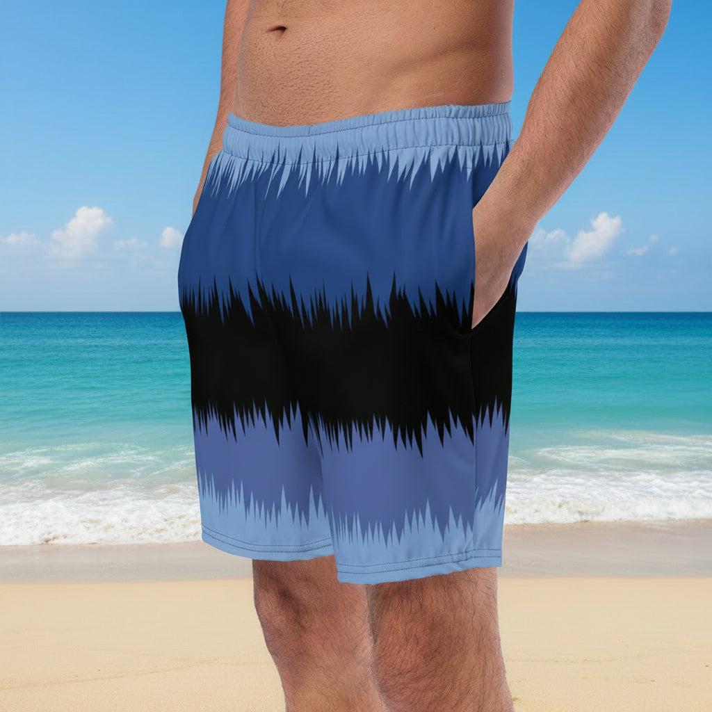 Person wearing blue and black striped swim shorts on a beach with ocean view
