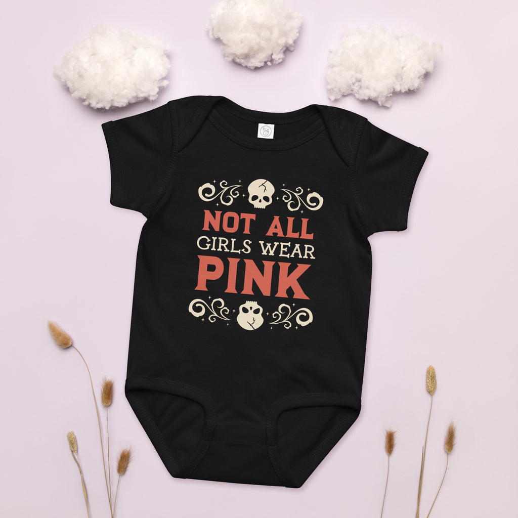 Black baby onesie with 'Not All Girls Wear Pink' text on a light pink background with decorative elements.