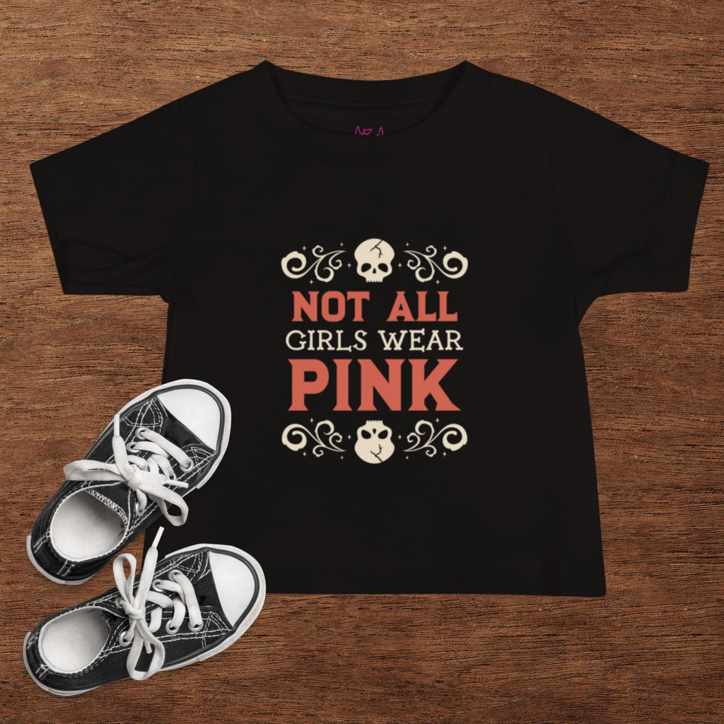 Black t-shirt with 'Not All Girls Wear Pink' text on a wooden surface with black and white sneakers.