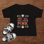 Black t-shirt with 'Not All Girls Wear Pink' text on a wooden surface with black and white sneakers.