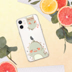 Phone case with a cute green dinosaur design on a yellow surface with sliced oranges and leaves.
