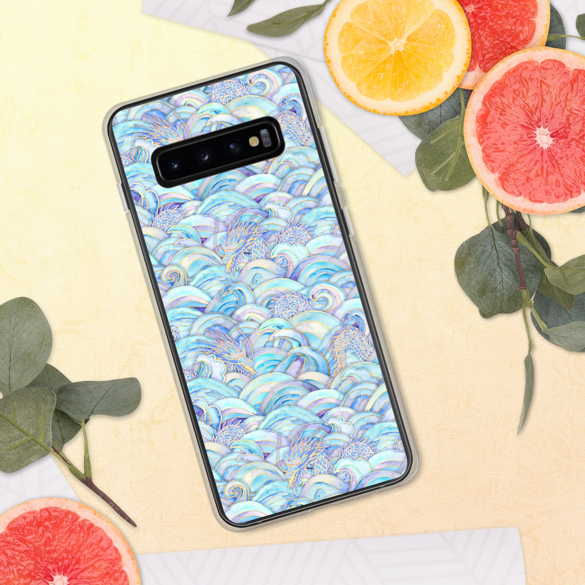 Phone case with a colorful wave pattern on a yellow surface with fruit and leaves.