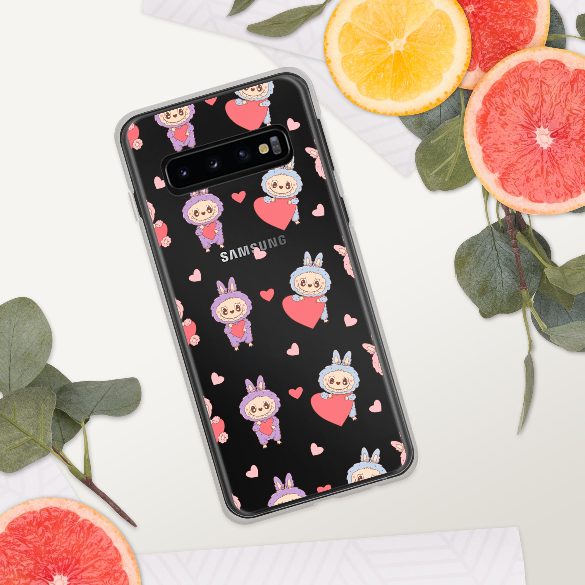 Samsung phone case with cartoon character and heart pattern on a white surface with fruit and leaves.