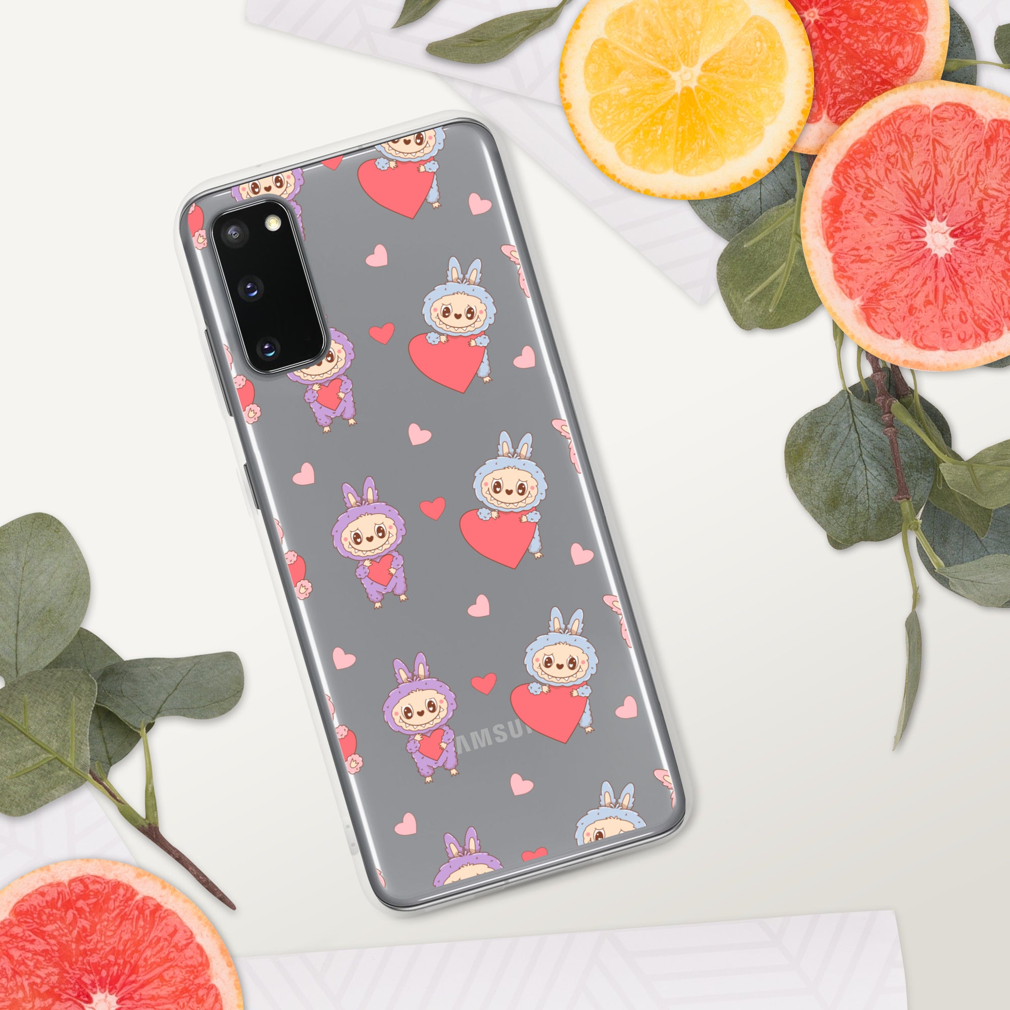 Phone case with cartoon character and heart pattern on a surface with fruits and leaves