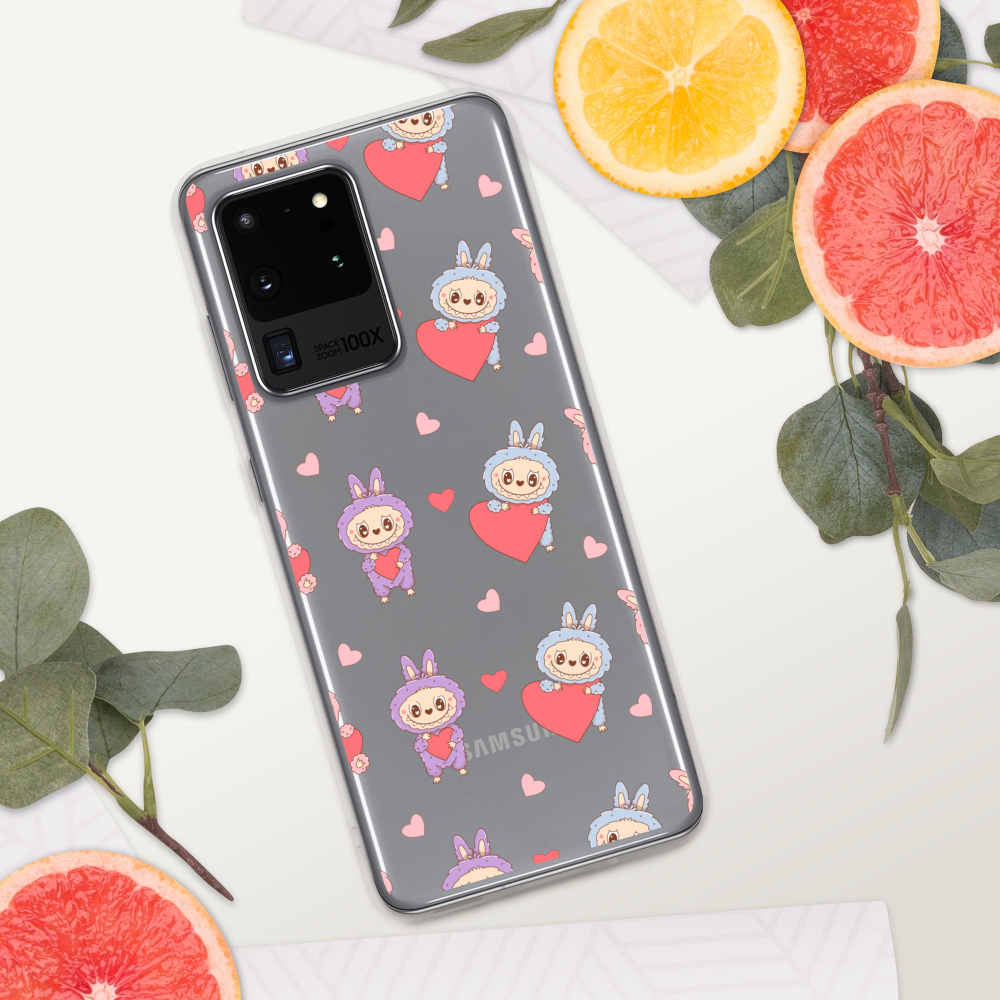 Phone case with cartoon character and heart pattern on a white surface with fruits and leaves.