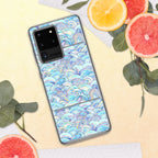 Phone case with a colorful wave pattern on a yellow surface with fruit and leaves.
