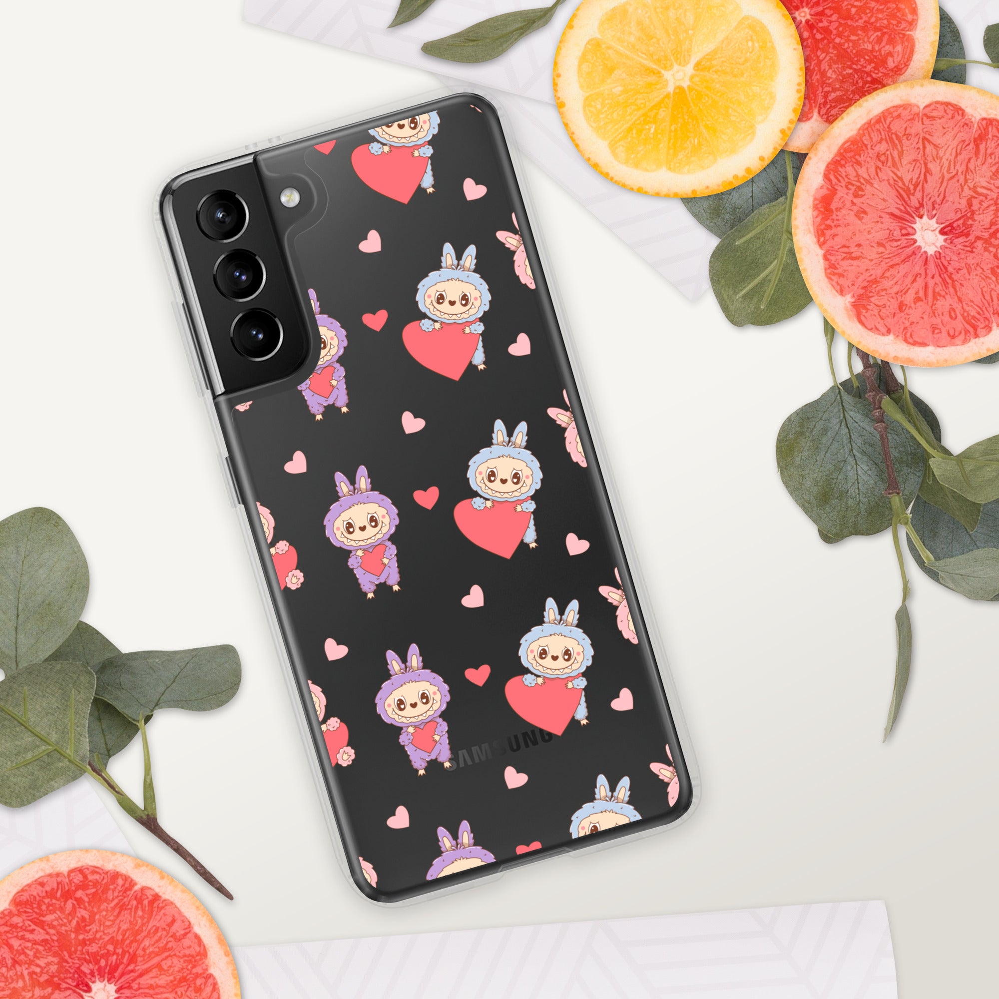 Phone case with cartoon character and heart pattern on a white surface with fruit and leaves.