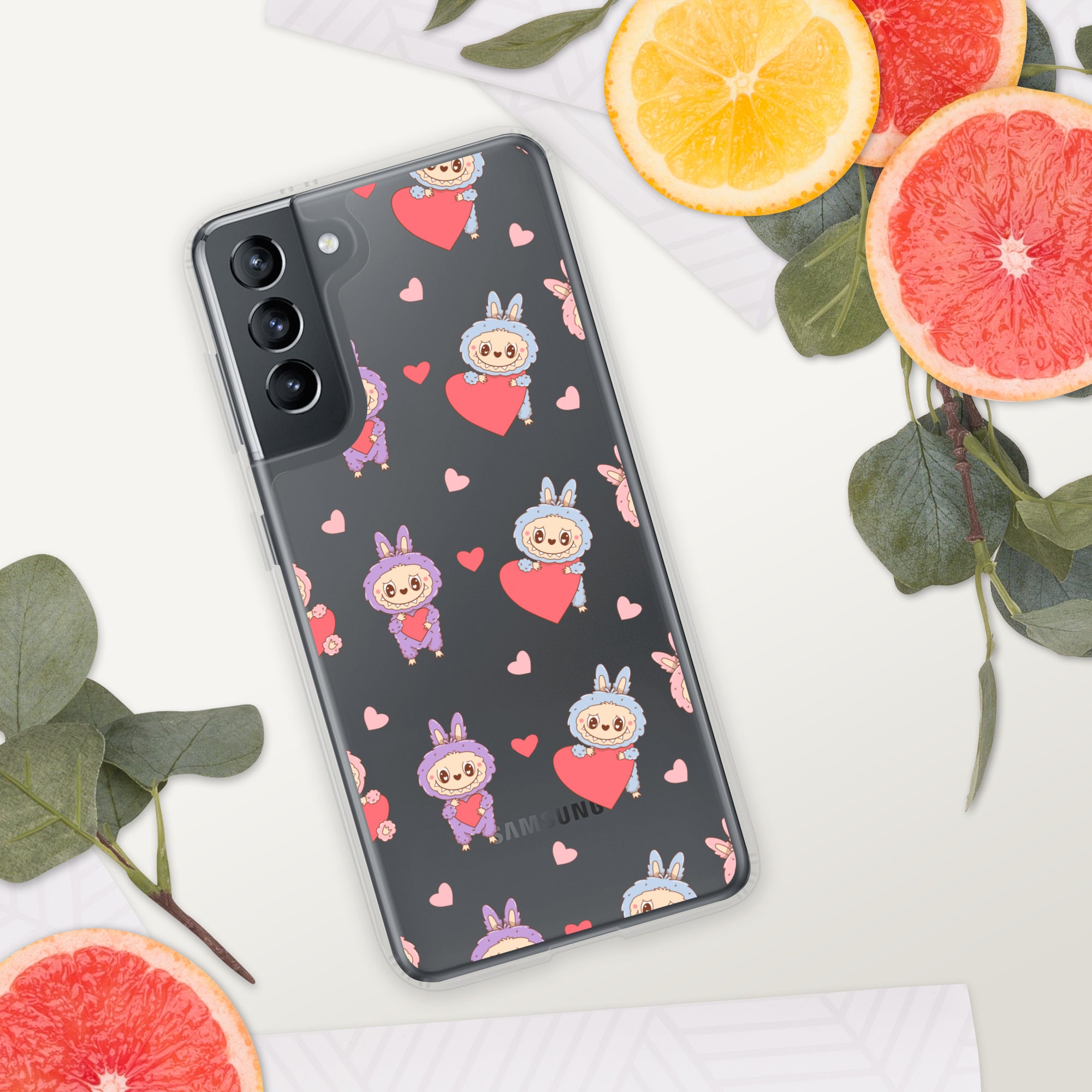 Phone case with cartoon character and heart pattern on a white surface with fruit and leaves.