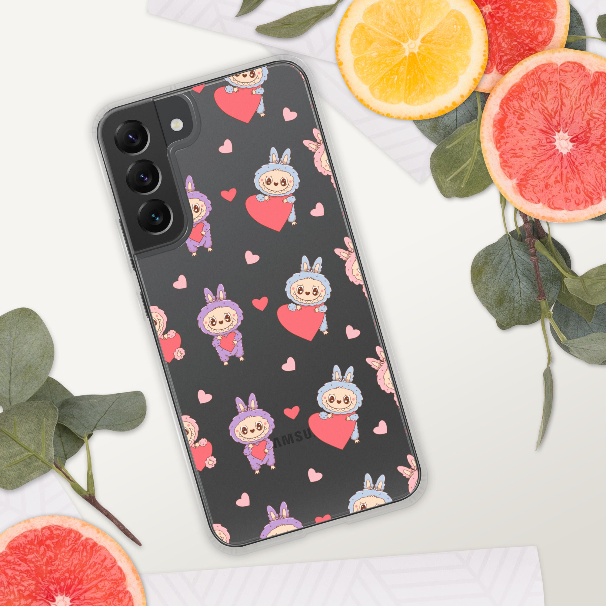 Phone case with cartoon character and heart pattern on a white surface with fruit and leaves.
