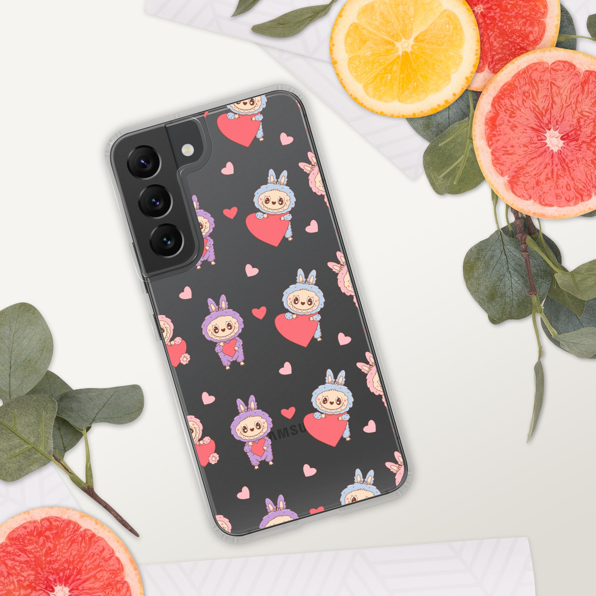 Phone case with cartoon character and heart pattern on a white surface with fruit and leaves.