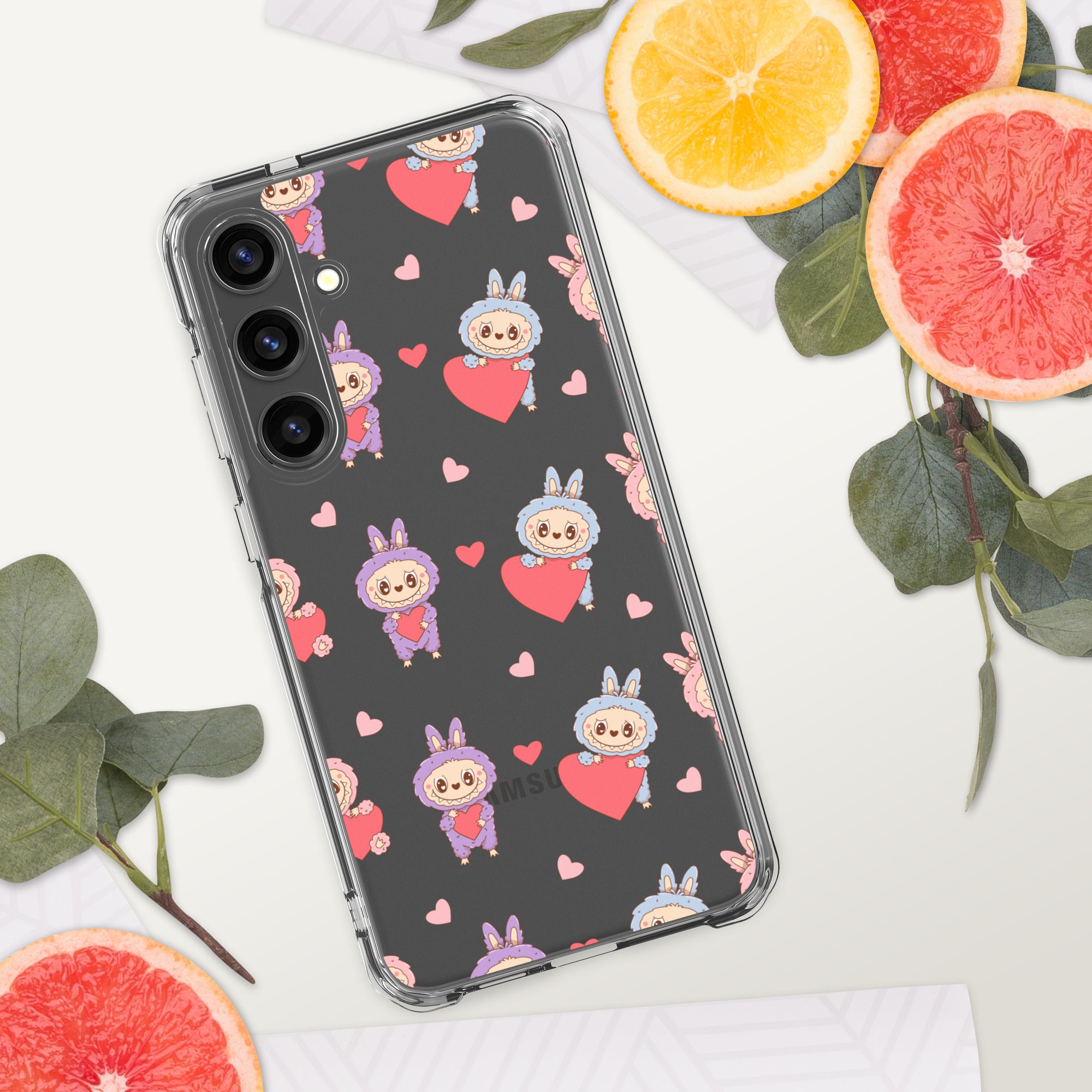 Phone case with cartoon character and heart pattern on a white surface with sliced oranges and leaves.