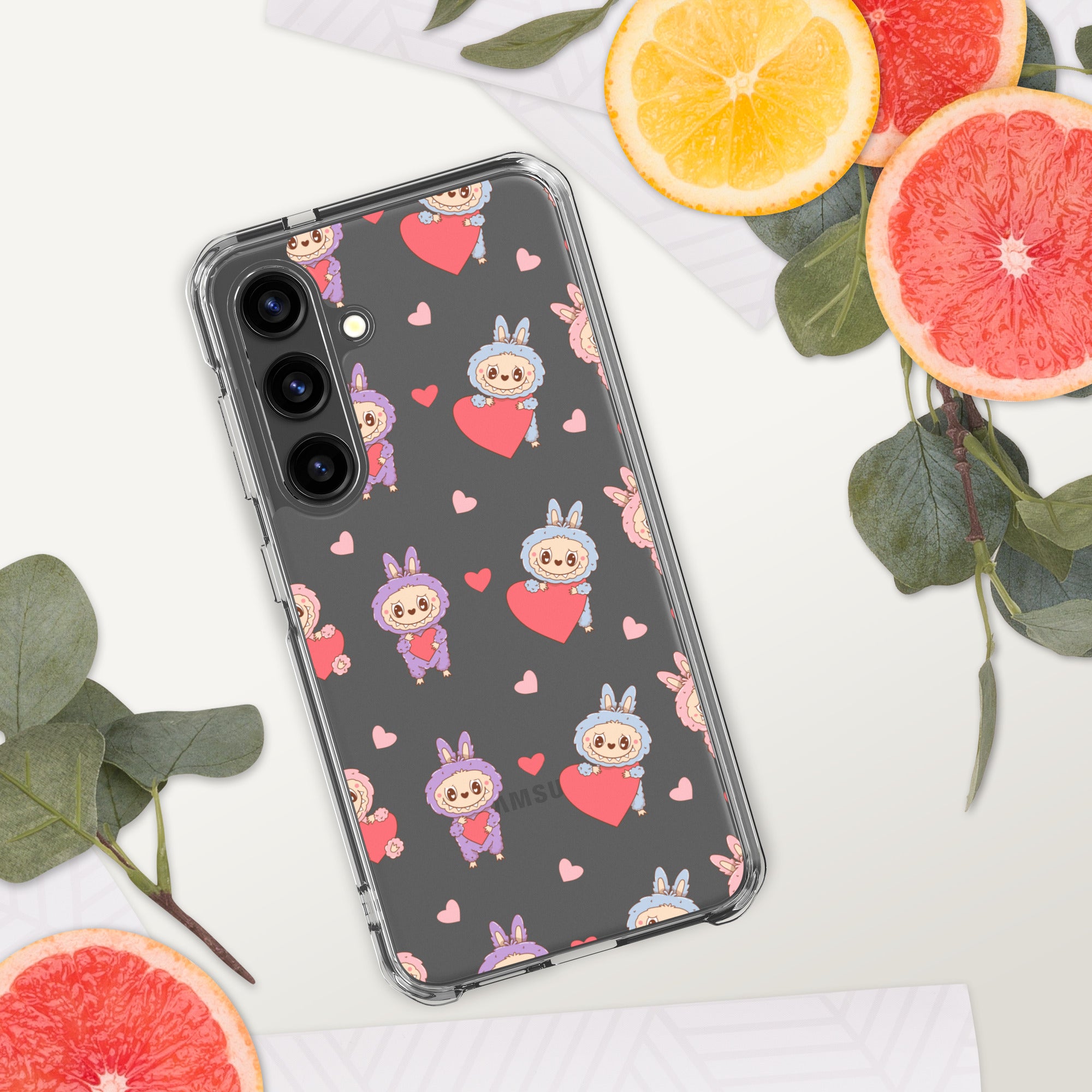 Phone case with cartoon character and heart pattern on a white surface with fruits and leaves.