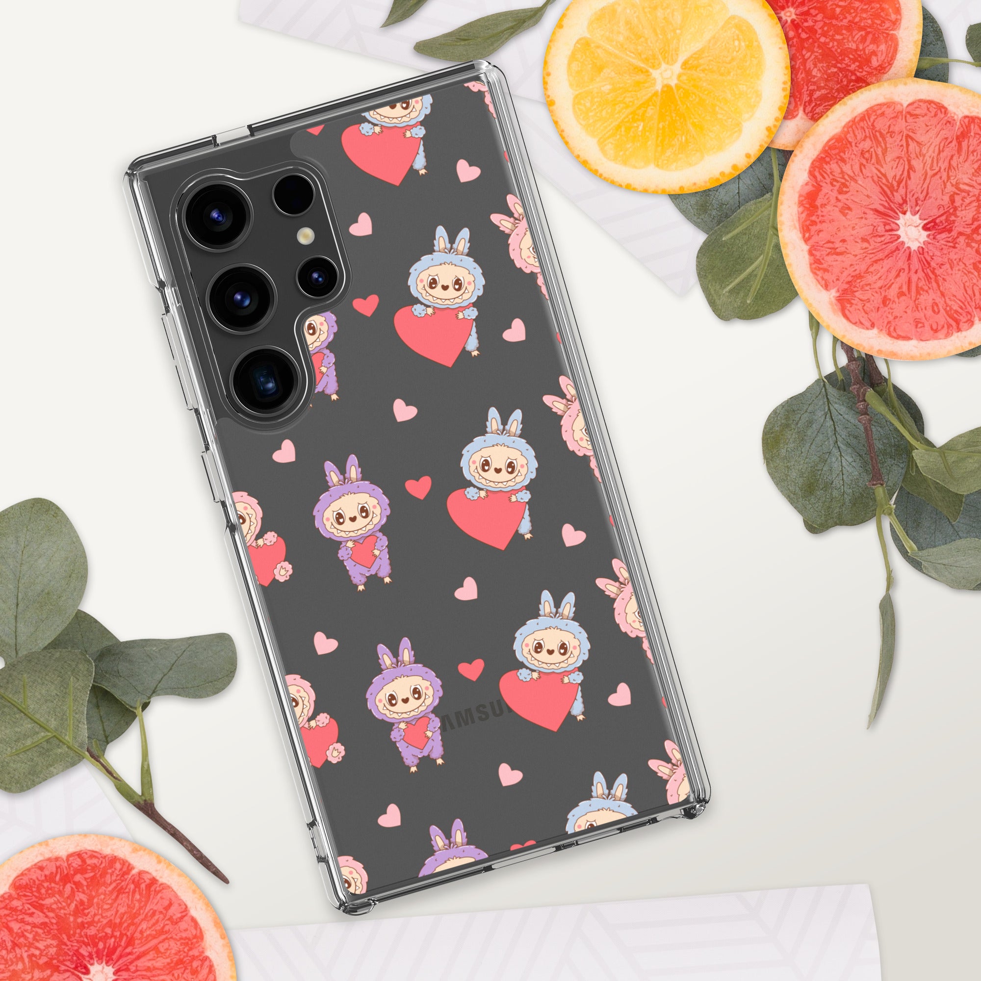 Phone case with cartoon character and heart pattern on a white surface with fruit and leaves.