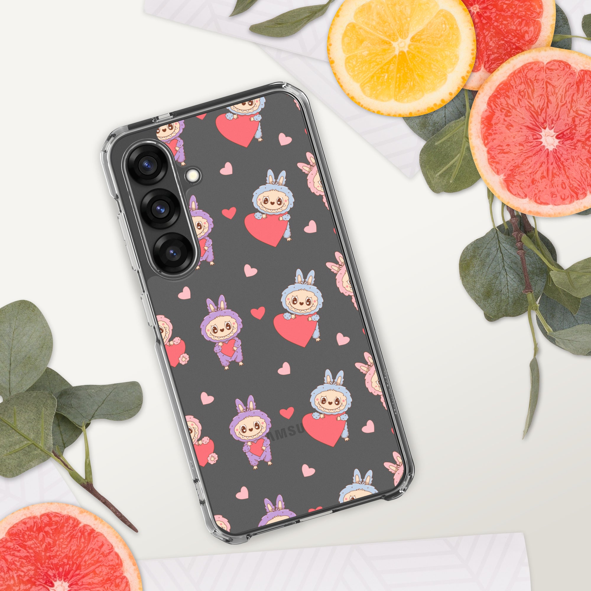 Phone case with cartoon character and heart pattern on a white surface with fruit and leaves.