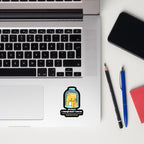 Laptop with a sticker on the palm rest area, next to a phone, pencil, and pen on a white surface.