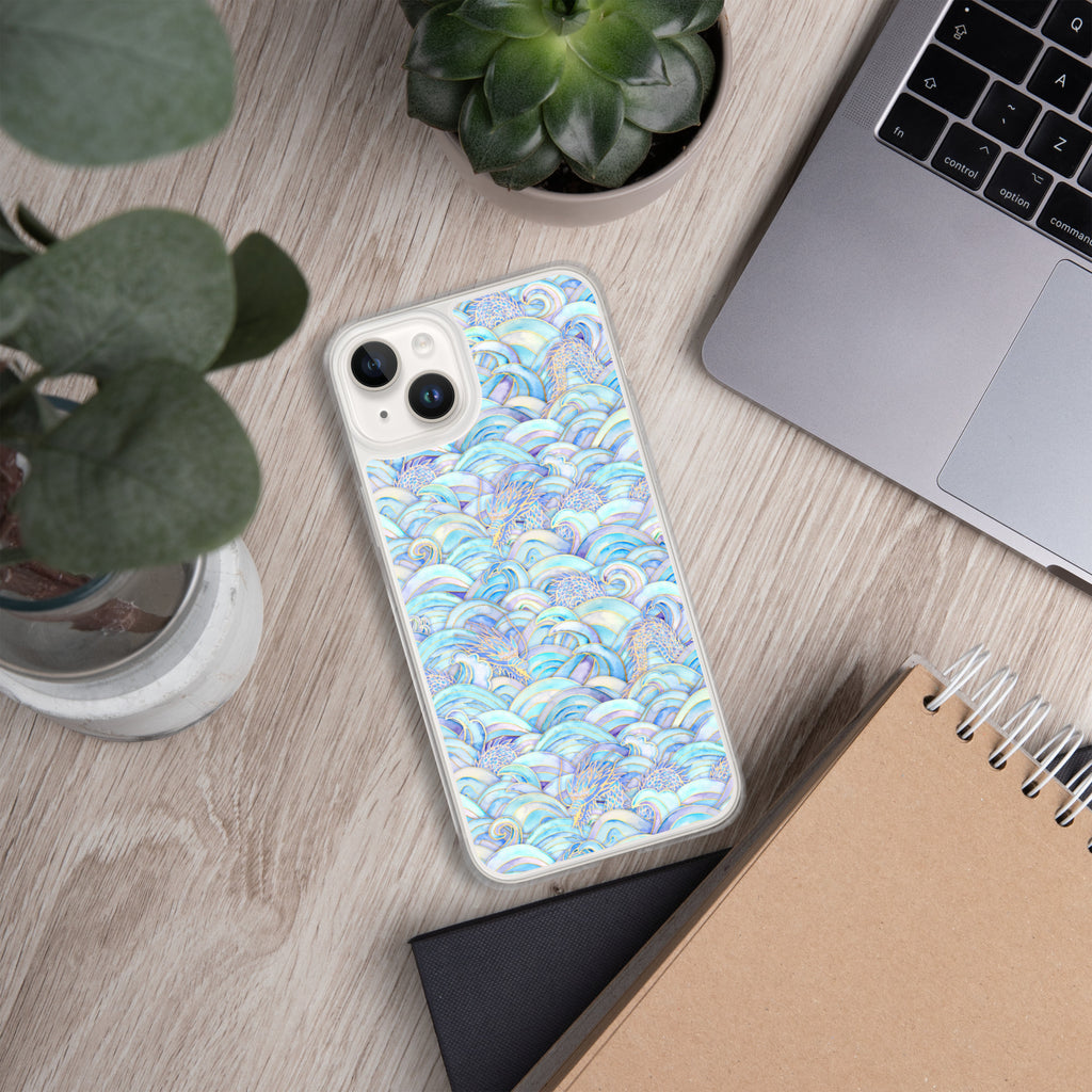Phone case with blue and white pattern on a wooden desk with laptop, notebook, and plant.