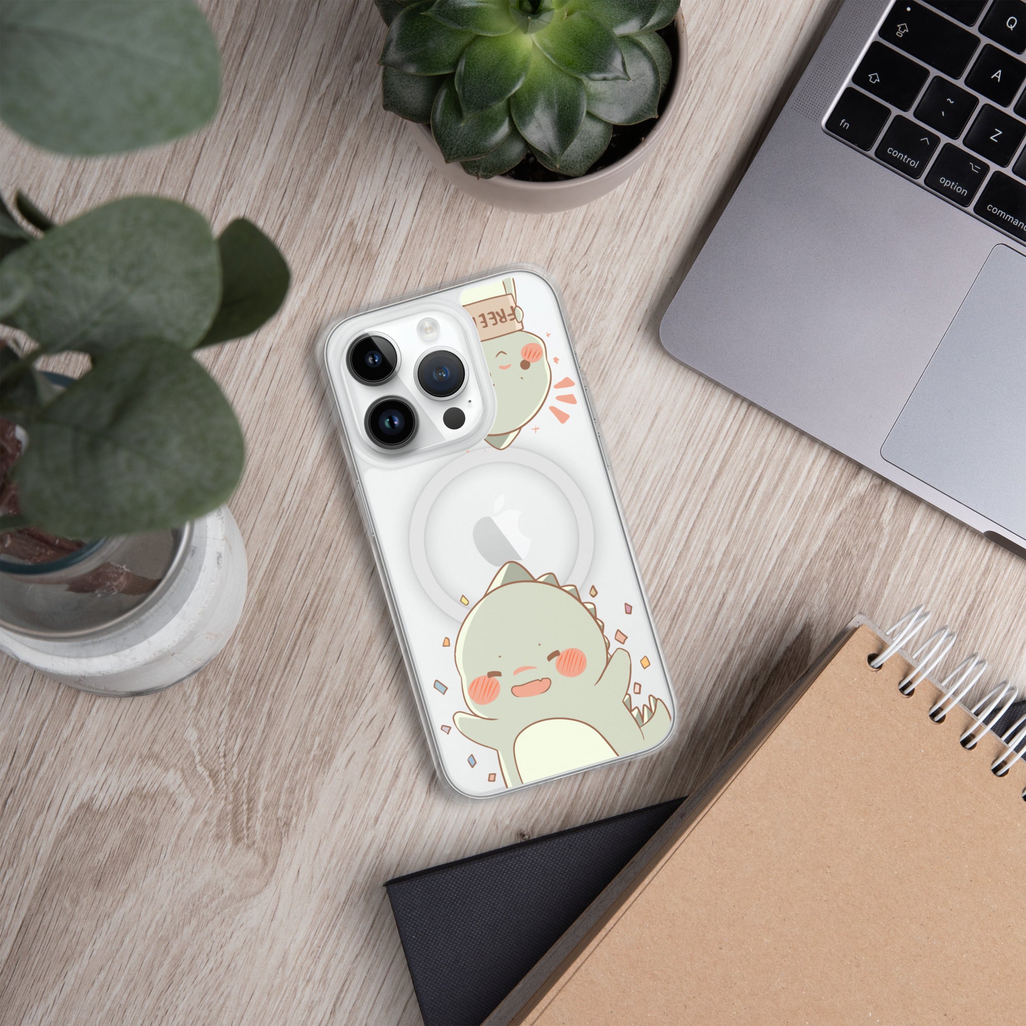 Phone case with a cute design on a wooden desk with a laptop and plants.