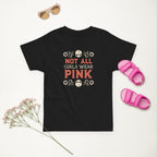 Black t-shirt with 'Not All Girls Wear Pink' text, pink sandals, and dried flowers on a white background