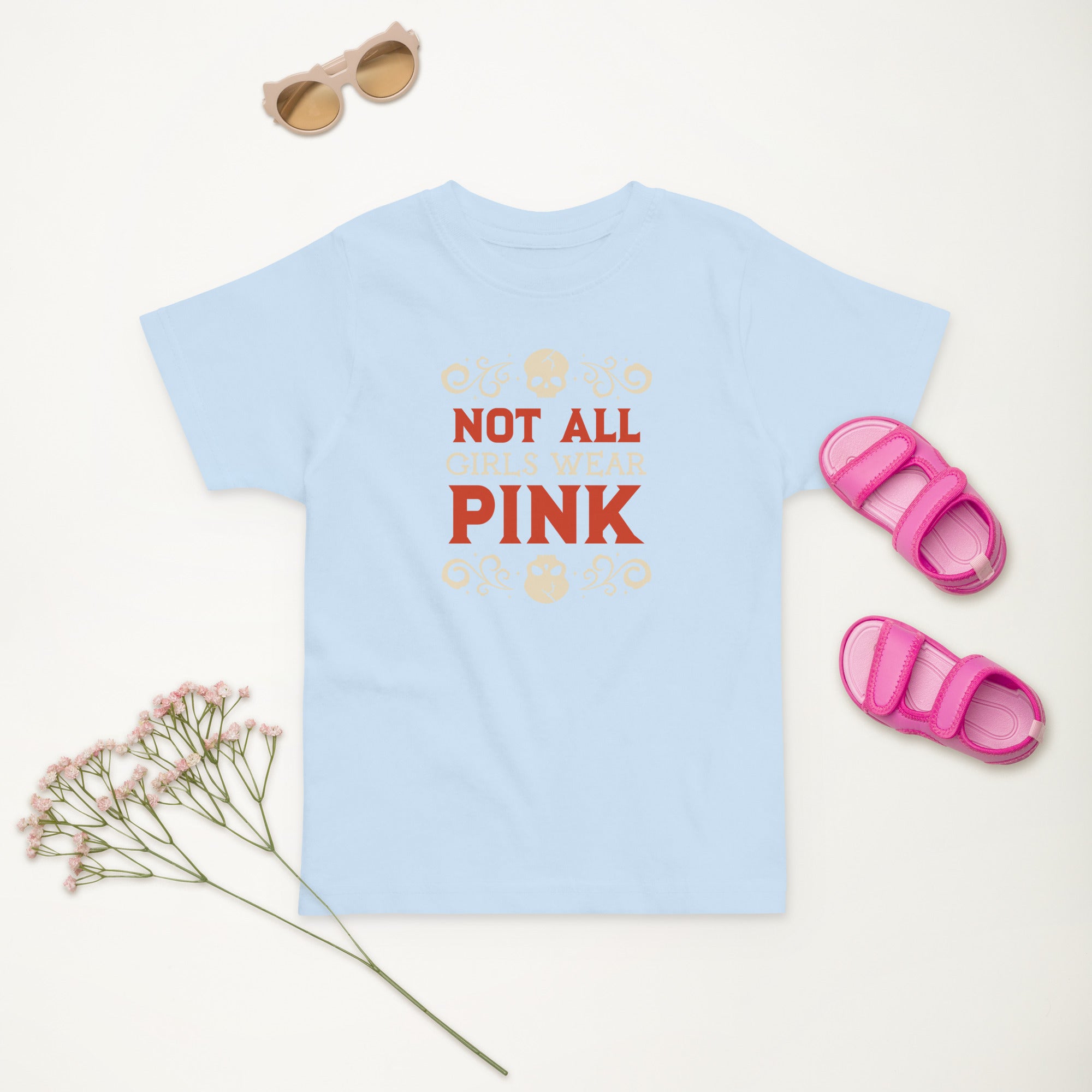 Light blue t-shirt with 'Not All Pink' text, pink sandals, and sunglasses on a white background