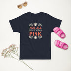 Navy blue t-shirt with 'Not All Girls Wear Pink' text, pink sandals, and sunglasses on a light background